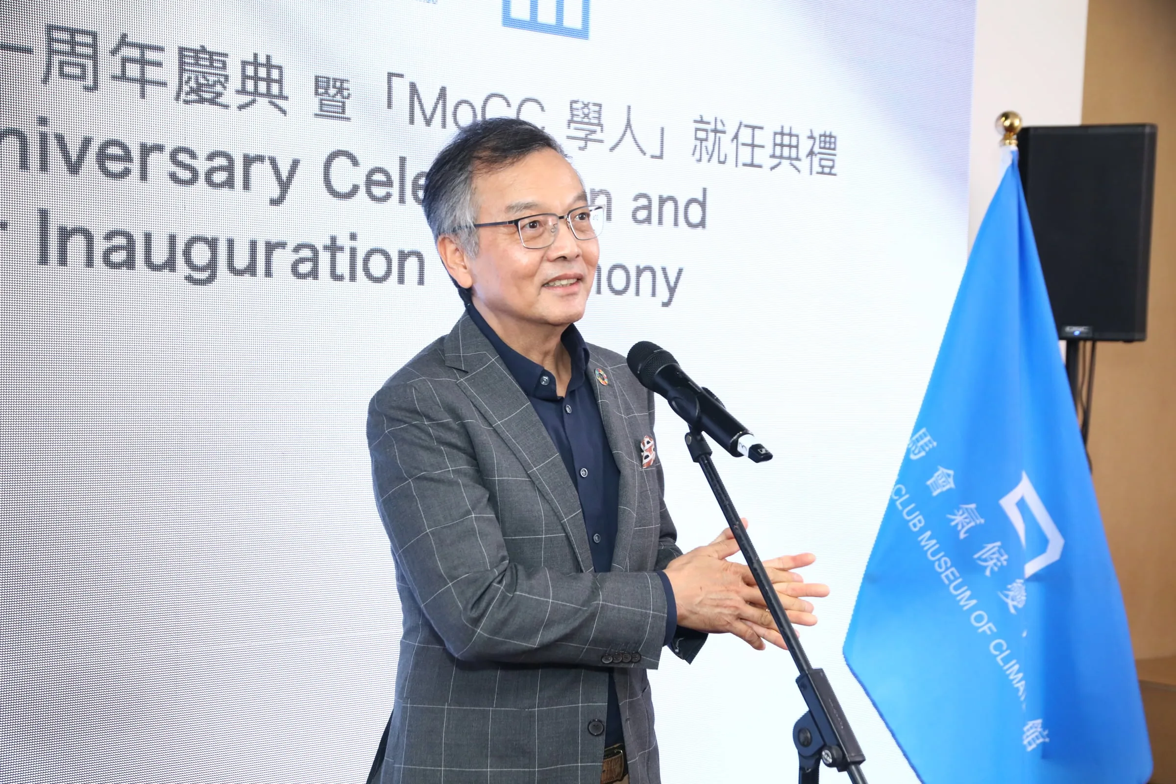 A speaker in a grey jacket addressing the audience